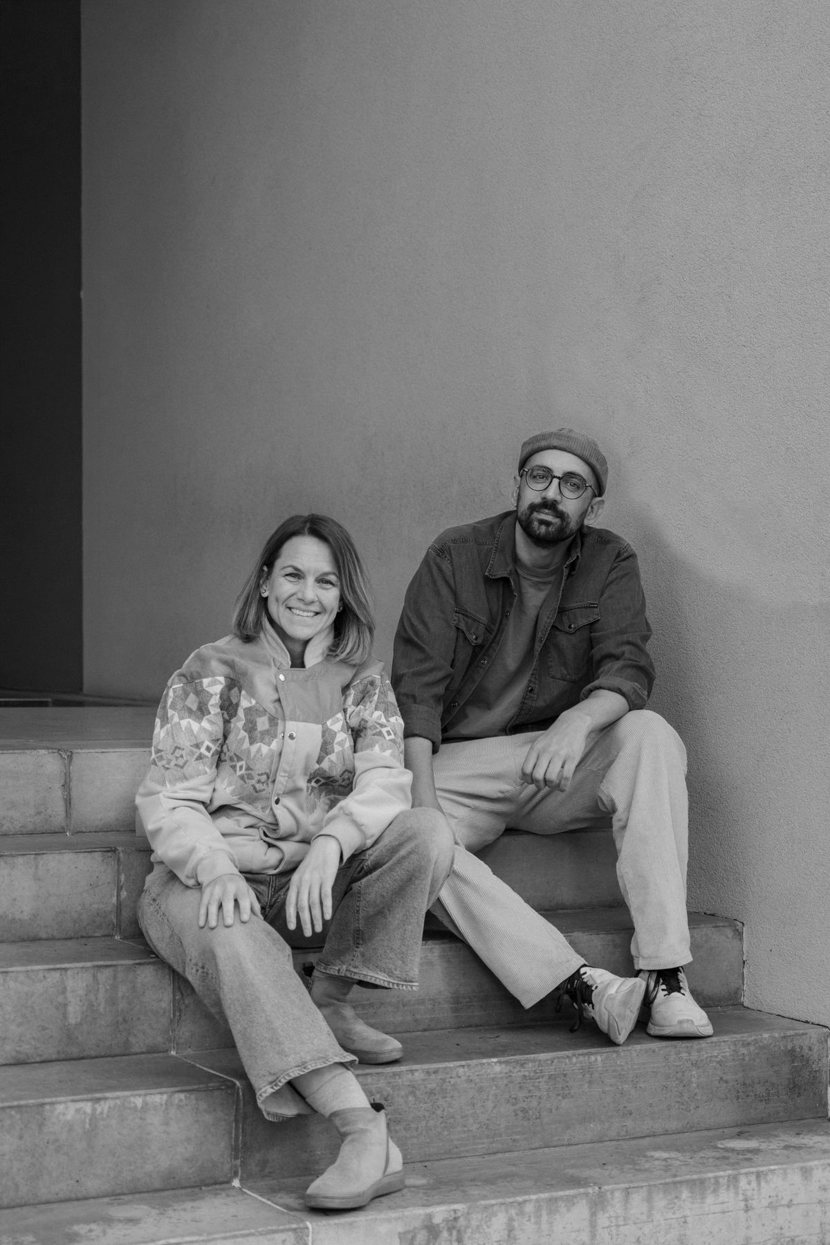 Tina und Nihad, die Gründer von Naloop, sitzen auf einer Steinbank, vor ihnen vier nachfüllbare Deos